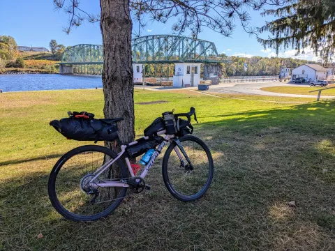 Bicycle leaning against tree along Erie Canal shore.