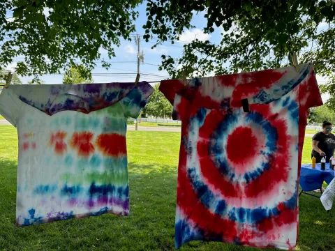 Tie dyed T-shirts hanging on line to drip dry.