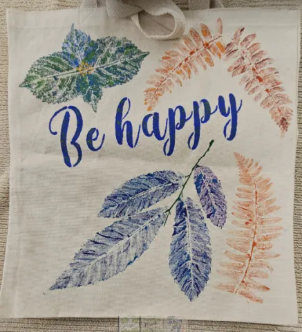 Italic text "Be happy" surrounded by colorful leaf prints.